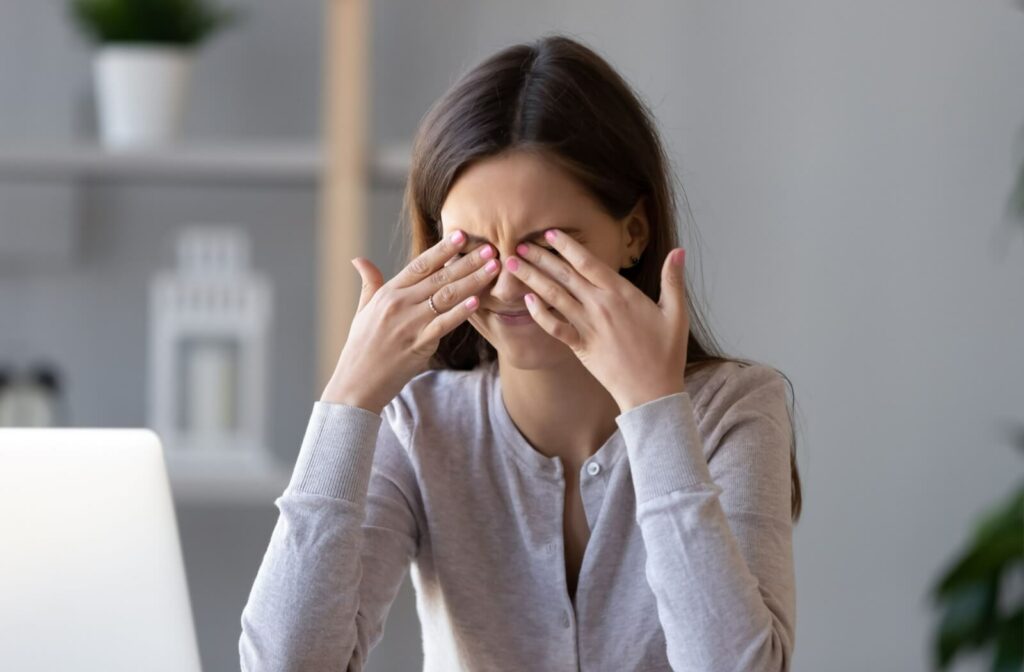 A young woman rubbing her dry, irritated eyes.